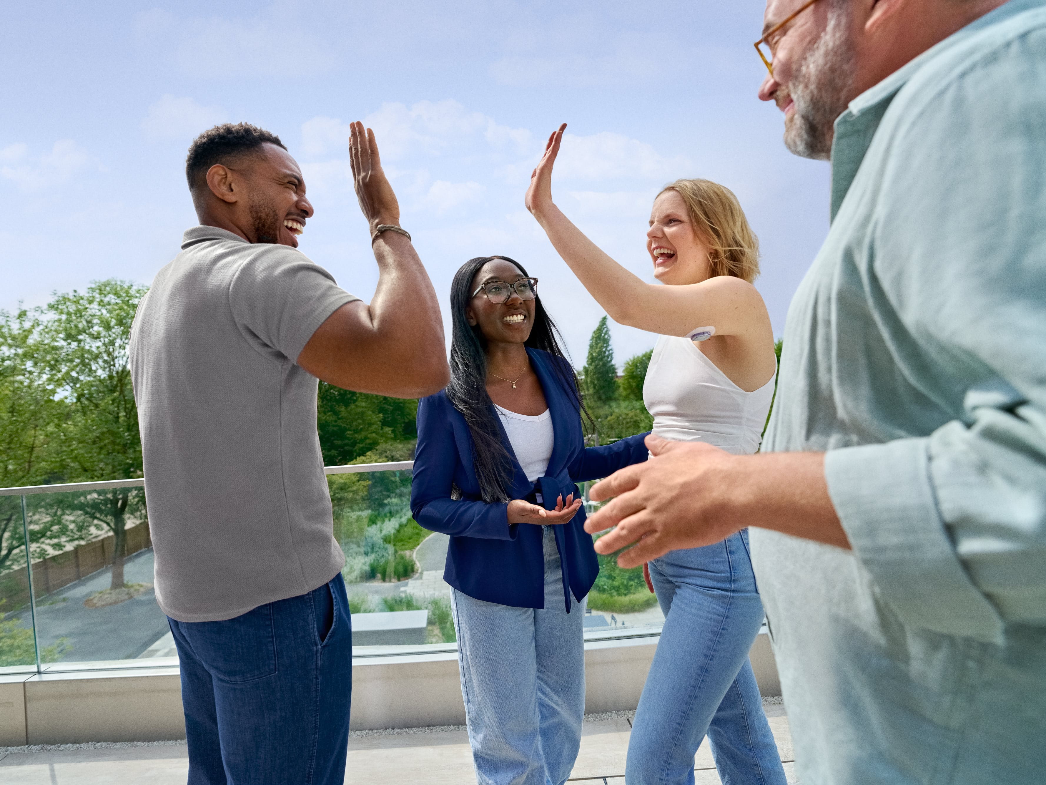 Group of colleagues outdoors celebrating together with high-fives on a terrace overlooking greenery