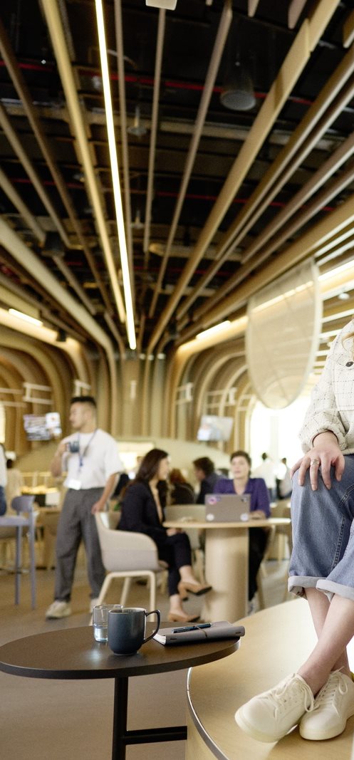 Interior of a modern collaborative workspace with wooden ceiling beams, lounge seating and people working and socialising in the background.